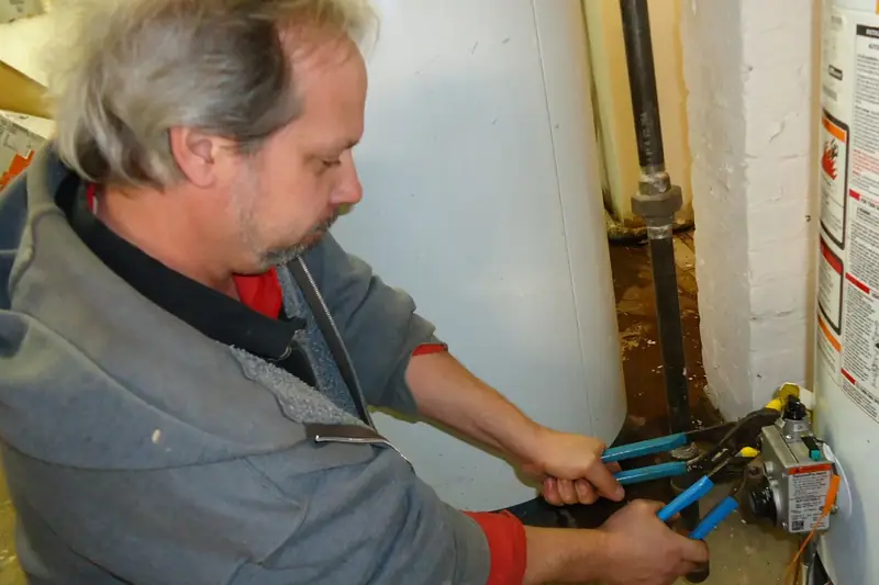 Plumber tightening a water heater fitting