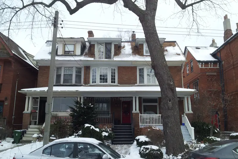 A large brick house with a wide front porch in winter