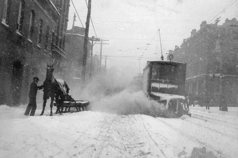 Workers and a streetcar clearing deep snow on Queen Street East in Toronto around 1900